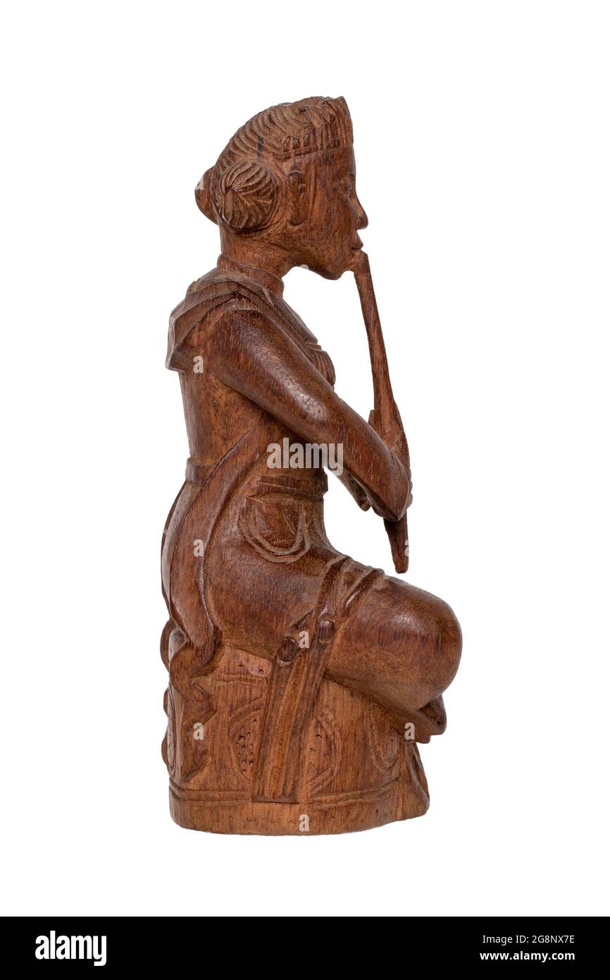 Nahaufnahme einer antiken geschnitzten Holzfigur eines asiatischen Mannes, der sitzt und ein Musikinstrument spielt. Eine geschnitzte Skulptur isoliert auf weißem Hintergrund Stockfoto