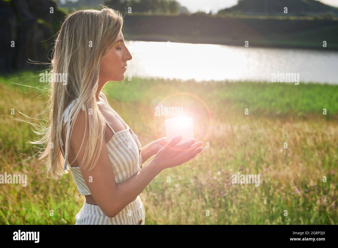Blonde Mädchen üben Meditation mit einer Kerze in der Morgendämmerung Stockfoto
