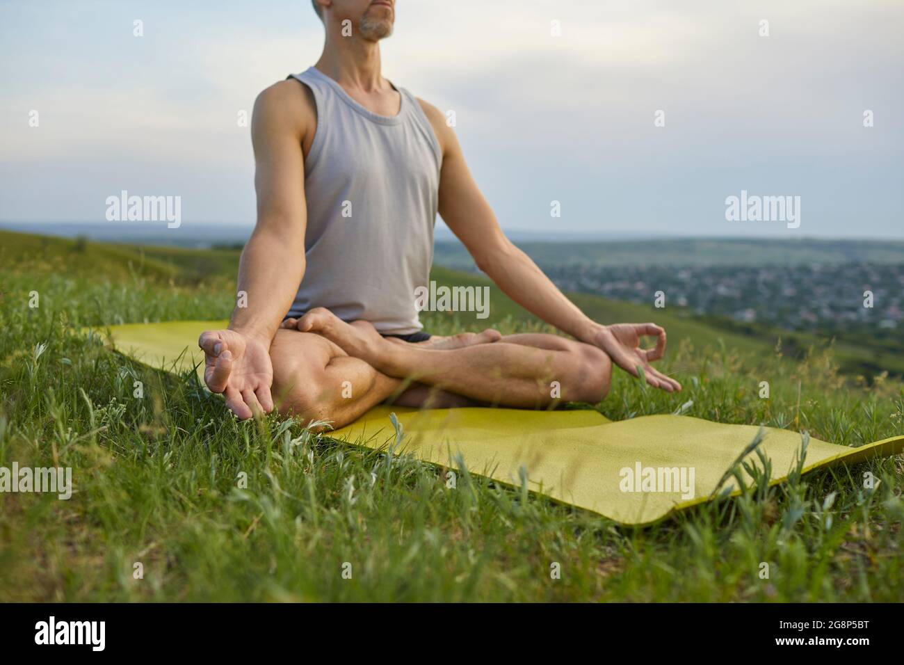 Männlicher Yoga-Liebhaber, der sich entspannt und inneren Frieden erreicht, praktiziert Meditation in der Natur Stockfoto