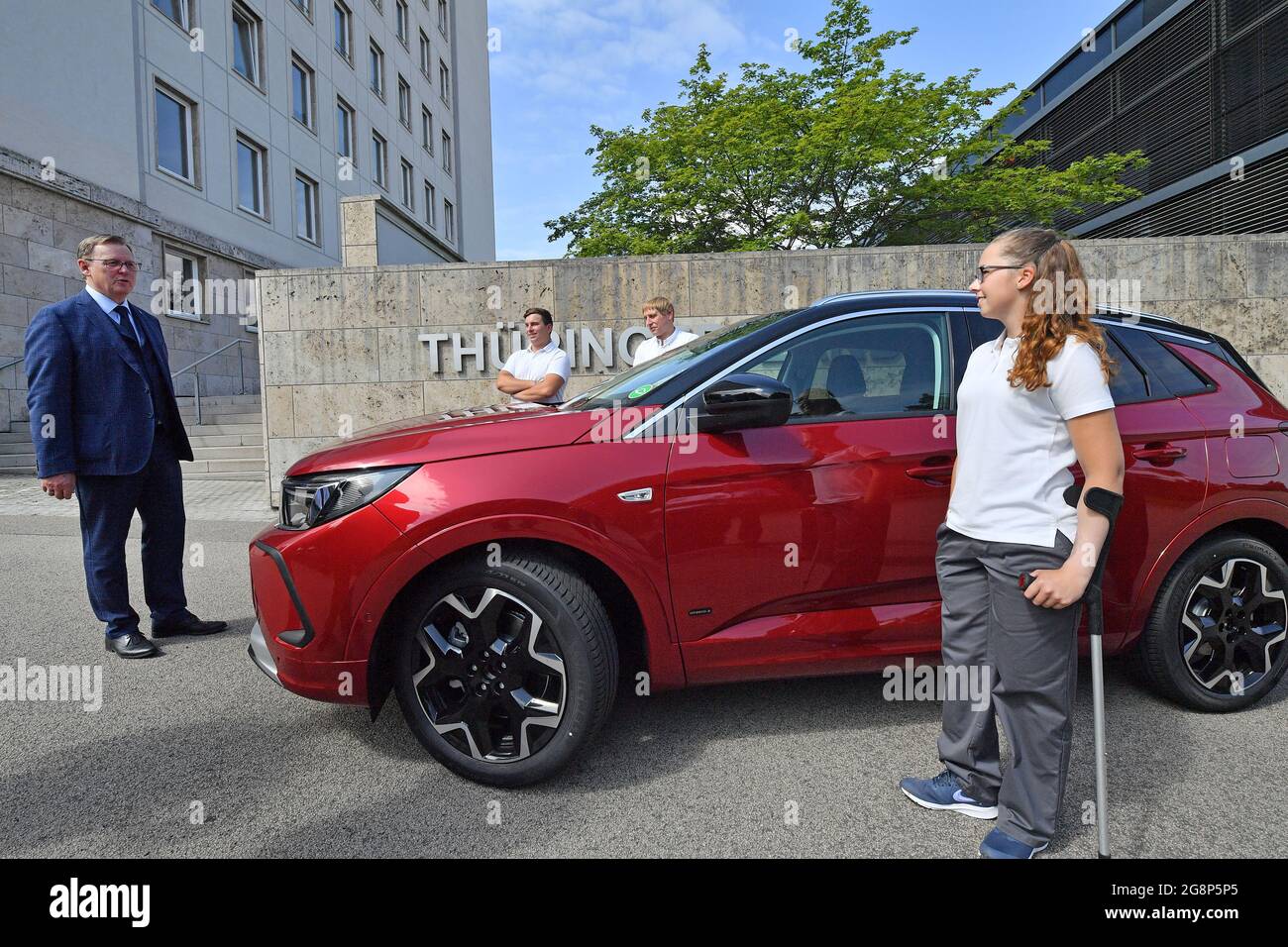 Erfurt, Deutschland. Juli 2021. Vor dem Thüringer landtag stehen Bodo Ramelow (die Linke, l-r), Jonas Bertl, Opel-Auszubildender, Eric Liebetrau, betriebsratsmitglied bei Opel Eisenach, und Anna Sophie Braun, Opel-Auszubildender. Der Austausch mit den Auszubildenden im Opel-Werk Eisenach fand am Rande der landtagsversammlung statt. Quelle: Martin Schutt/dpa-Zentralbild/dpa/Alamy Live News Stockfoto