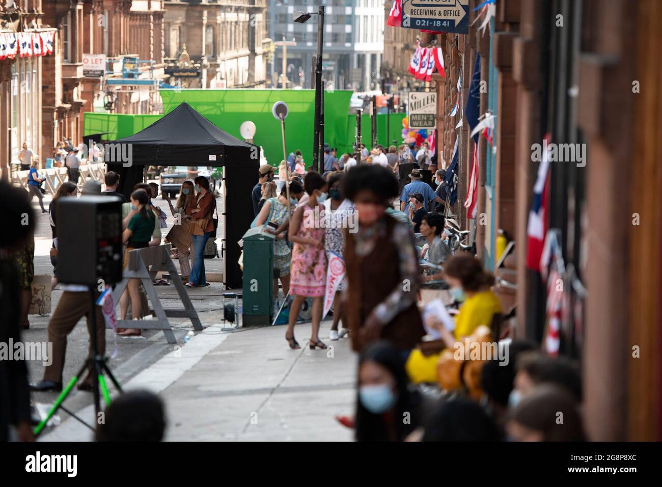 Glasgow, Schottland, Großbritannien. 21. Juli 2021. IM BILD: Cast-Mitglieder werden gesehen, wie sie eine kurze Pause machen, bevor die nächste Aufnahme gedreht wird. Dreharbeiten am Set von Indiana Jones 5 mitten im Stadtzentrum von Glasgow, als der Hollywood-Blockbuster Glasgow als New York City aufstellte. Eine vollständige Produktion ist zu sehen, mit einer großen Besetzung, Produzenten und Extras. Das Stadtzentrum wurde so verändert, dass alle Ladenfronten und Gebäude wie 1959 Amerika aussehen. Quelle: Colin Fisher Stockfoto