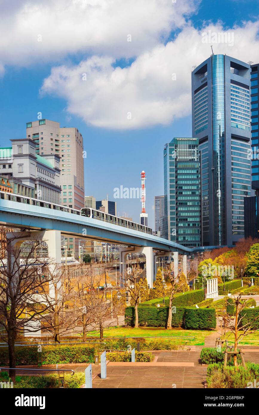 Öffentliche Verkehrsmittel in Tokio.Züge der Yurikamome-Linie und Shinkansen fahren in der Nähe der modernen Wolkenkratzer von Shimbashi vorbei Stockfoto