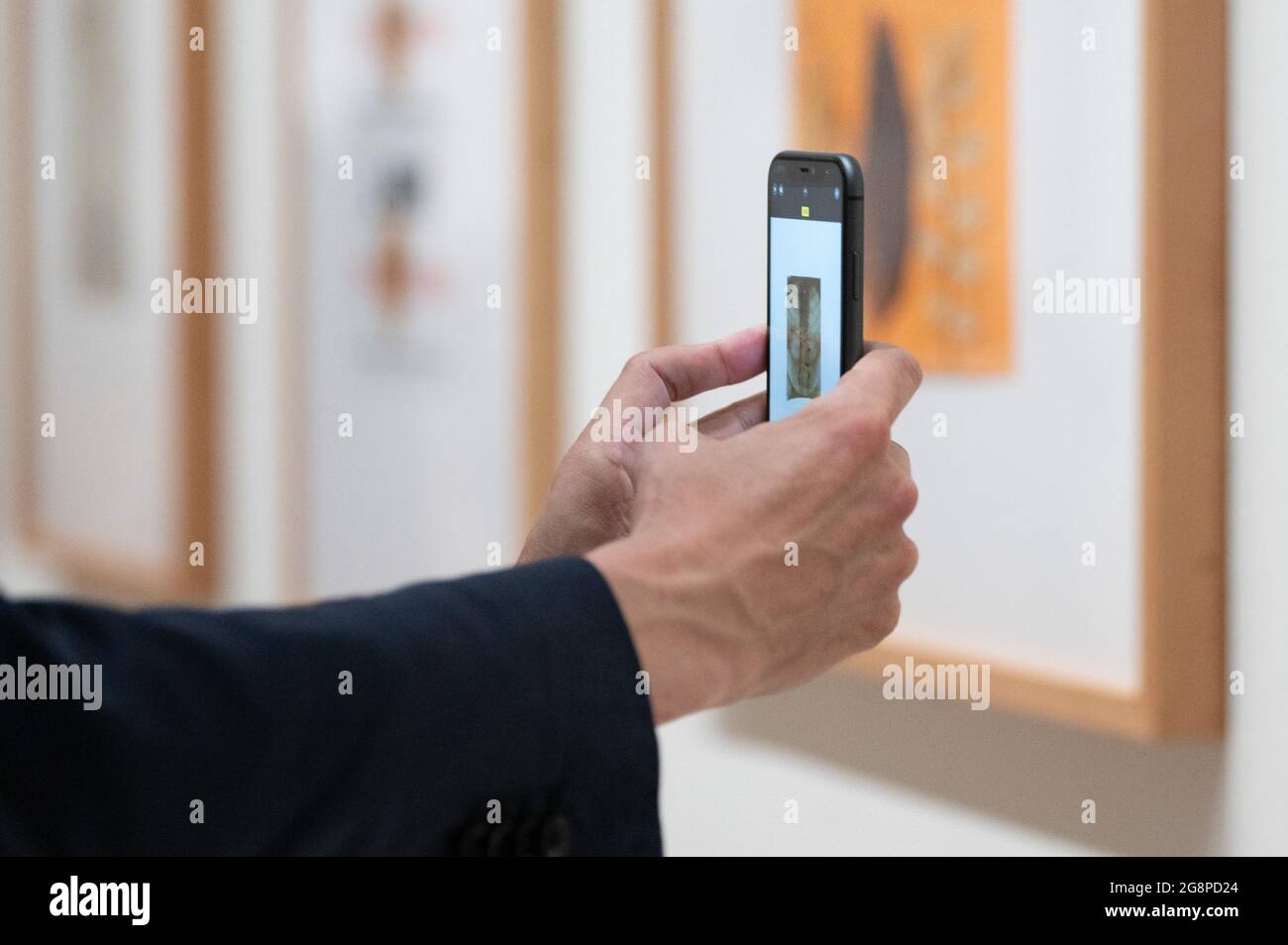 Dresden, Deutschland. Juli 2021. Anlässlich des 100. Geburtstags des Installations- und Aktionskünstlers Joseph Beuys in der Ausstellung 'Line to Line, Sheet by Sheet' im Kupferstich-Kabinett im Residenzschloss macht ein Mann mit einem Smartphone ein Foto während einer Pressetour. Die Ausstellung (23. Juli bis 17. Oktober 2021) bietet mit 90 grafischen Arbeiten, die noch nie ausgestellt wurden, einen ersten Einblick in die Sammlung von Beuys-Zeichnungen, die in der Familie aufbewahrt wurden. Quelle: Sebastian Kahnert/dpa-Zentralbild/dpa/Alamy Live News Stockfoto