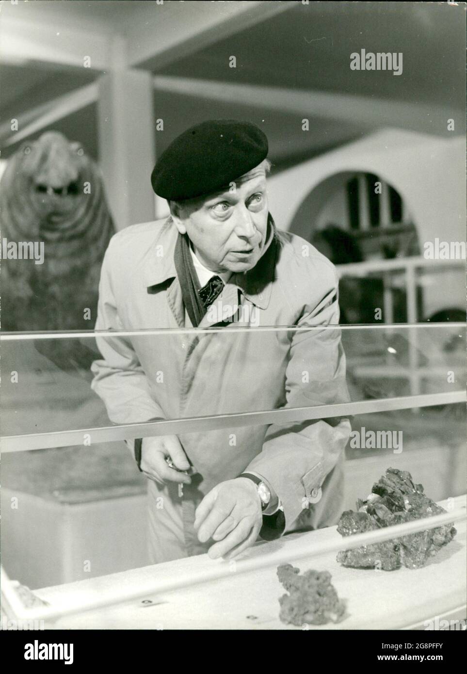 Szenenfoto aus der Folge 'Blinder Hass' der Krimierie 'dem Täter auf der Spur' mit Günther Lüders. Vor der Vitrine demonstriert Louis (Günther Lüders), wie er den Glimmerstein in der Mordnacht gestohlen hat. Gleich darauf gelgt es ihm zu fliegen.... Stockfoto