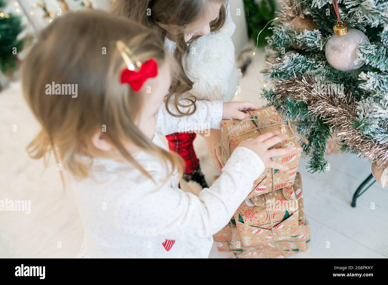 Zwei kleine entzückende Mädchen stehen über einem Stapel von Geschenken, während sie sehr aufgeregt sind, sie schnell, festlich und magische Atmosphäre der Winterferien zu öffnen Stockfoto