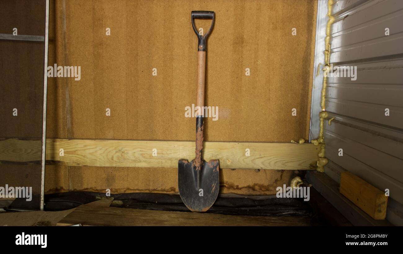 Ein Spatenstich gegen einen Holzhintergrund Stockfoto