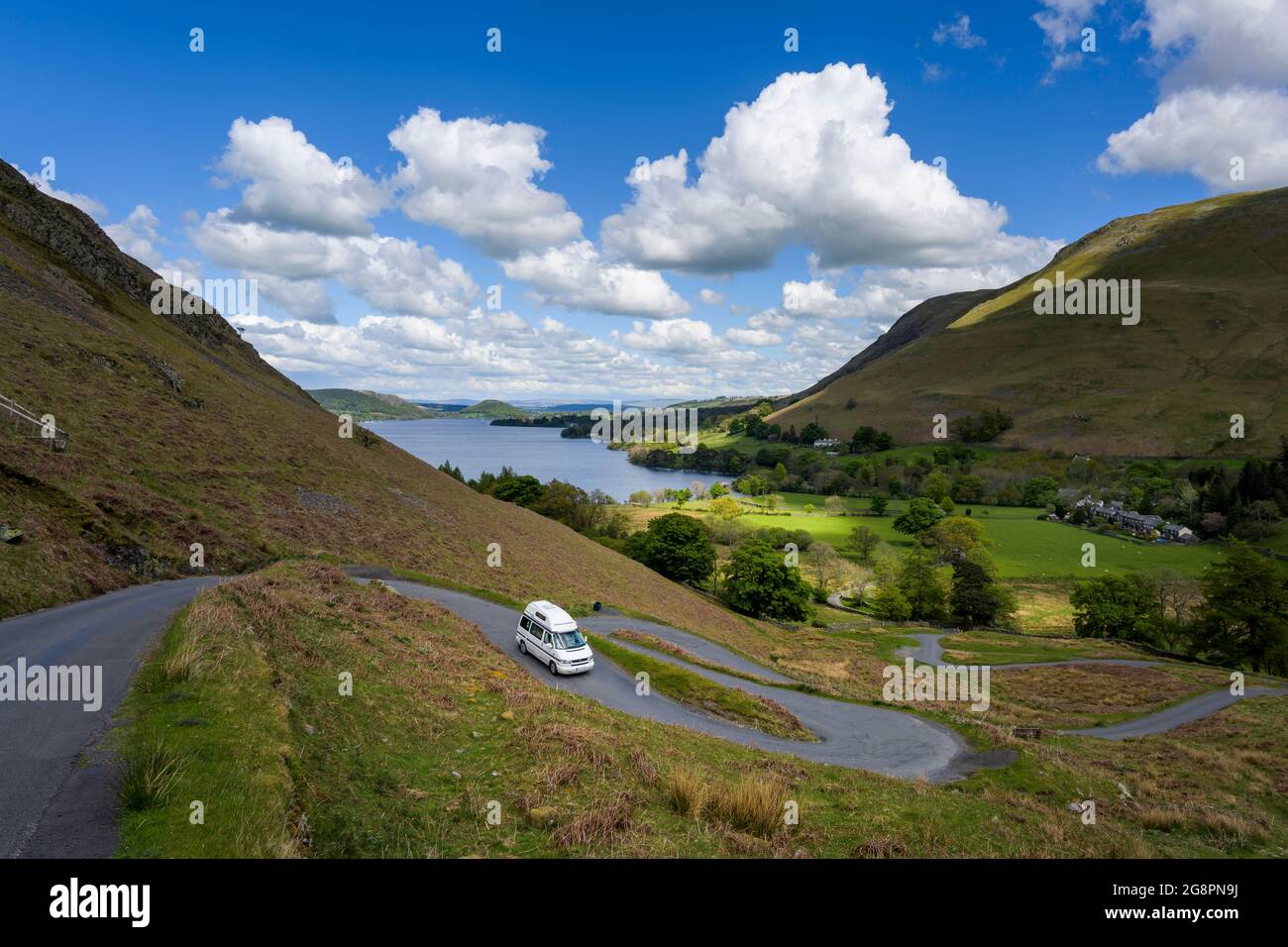 Ein VW-Wohnmobil, der die kurvenreiche Straße nach Howtown mit Ullswater im Hintergrund dekending. Stockfoto