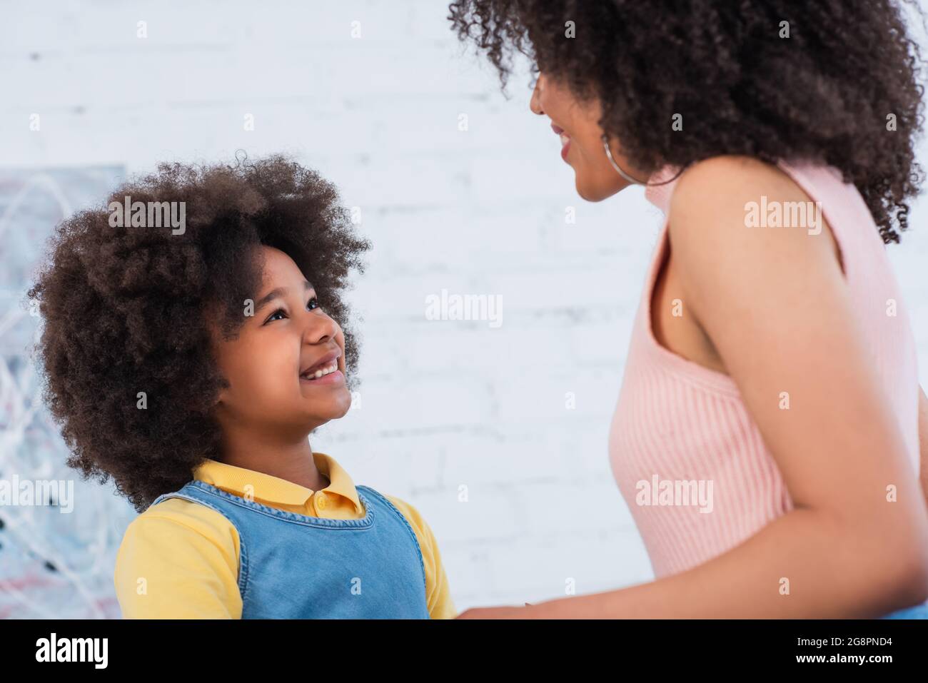 Lächelndes afroamerikanisches Kind, das die Eltern zu Hause ansieht Stockfoto