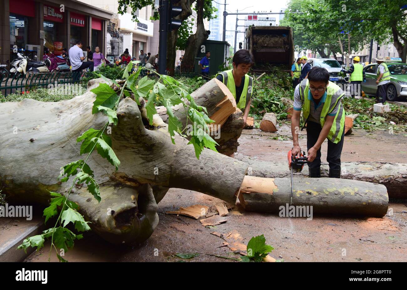 Zhengzhou, Chinas Provinz Henan. Juli 2021. Mitarbeiter entfernen umgestürzte Bäume von einer Straße in Zhengzhou, der zentralchinesischen Provinz Henan, 22. Juli 2021. Die chinesischen Behörden haben massive Rettungs- und Hilfsmaßnahmen eingeleitet, um auf Rekordregenstürme zu reagieren, die seit dem Wochenende die Provinz Henan in Zentralchina überschwemmt haben. In der Provinzhauptstadt Zhengzhou fielen ab Samstagabend über einen Zeitraum von drei Tagen 617.1 mm Niederschlag, fast so hoch wie der durchschnittliche jährliche Betrag der Stadt. Quelle: Zhu Xiang/Xinhua/Alamy Live News Stockfoto