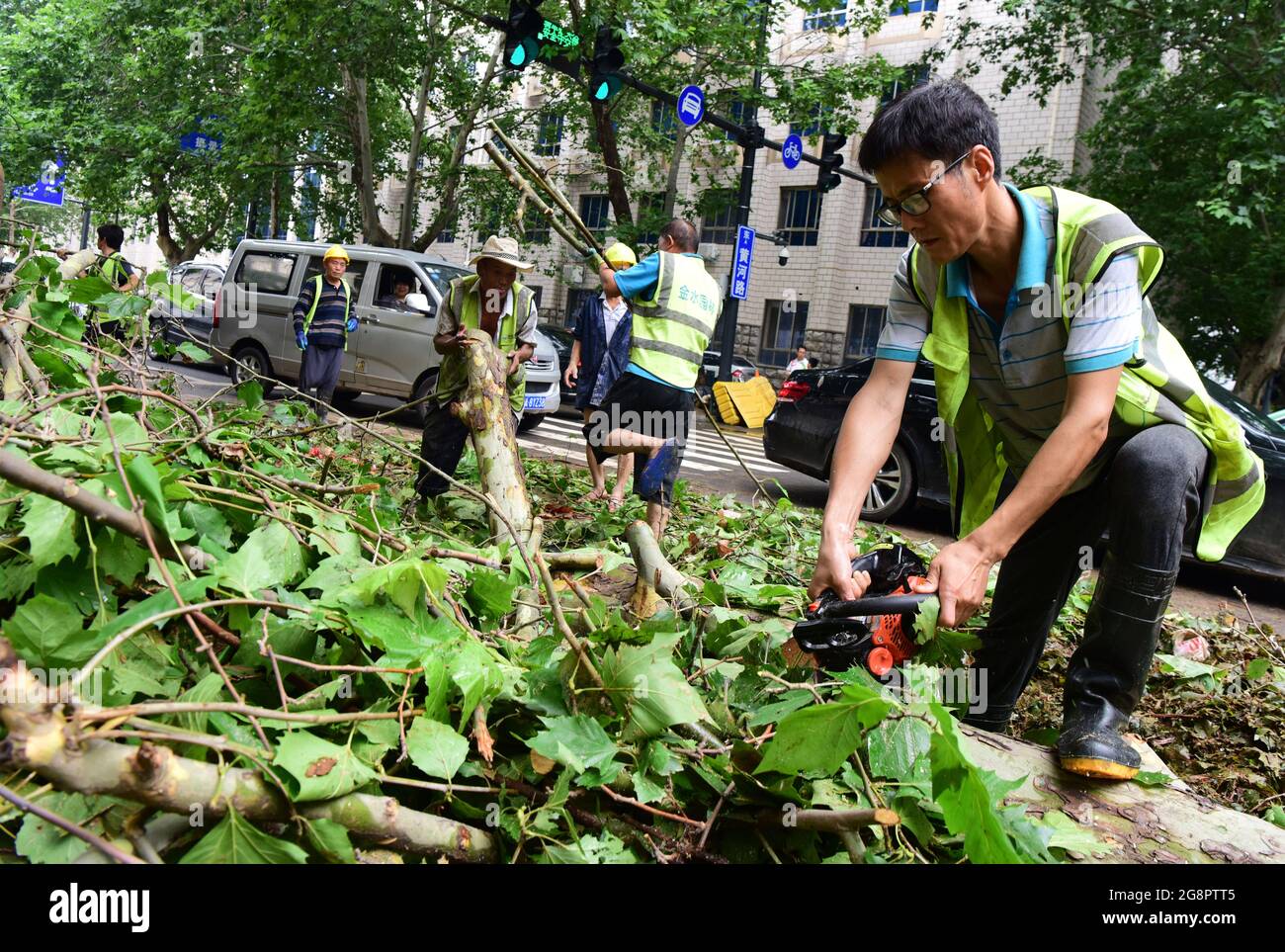 Zhengzhou, Chinas Provinz Henan. Juli 2021. Mitarbeiter entfernen umgestürzte Bäume von einer Straße in Zhengzhou, der zentralchinesischen Provinz Henan, 22. Juli 2021. Die chinesischen Behörden haben massive Rettungs- und Hilfsmaßnahmen eingeleitet, um auf Rekordregenstürme zu reagieren, die seit dem Wochenende die Provinz Henan in Zentralchina überschwemmt haben. In der Provinzhauptstadt Zhengzhou fielen ab Samstagabend über einen Zeitraum von drei Tagen 617.1 mm Niederschlag, fast so hoch wie der durchschnittliche jährliche Betrag der Stadt. Quelle: Zhu Xiang/Xinhua/Alamy Live News Stockfoto