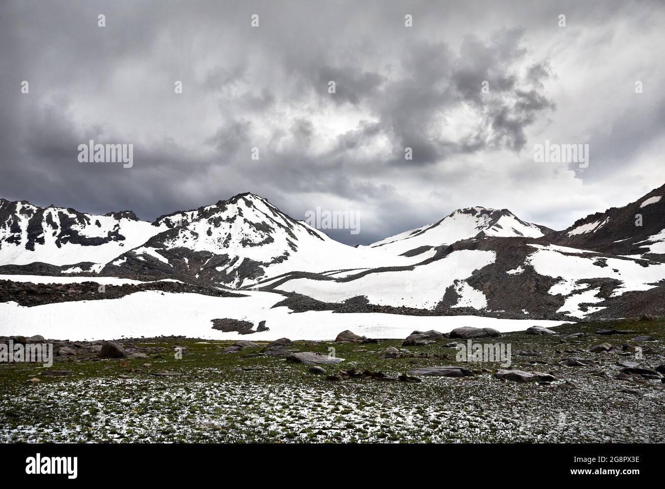 Schöne Landschaft des Bergtals mit Schneekappe Gipfel und gegen dunklen bewölkten Himmel. Outdoor- und Wanderkonzept Stockfoto