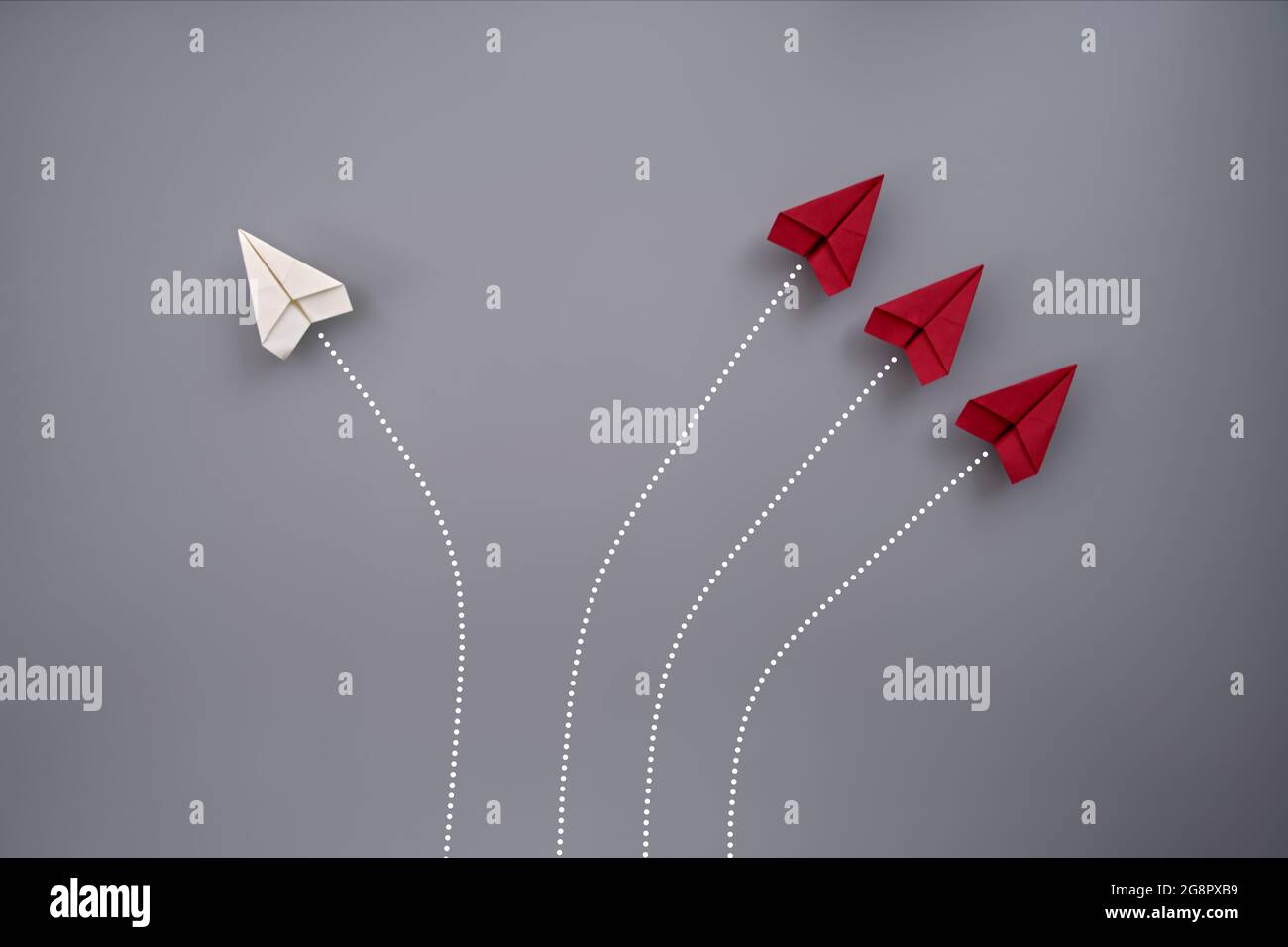 Vier gefaltete Papierflieger fliegen vor grauem Hintergrund Stockfoto