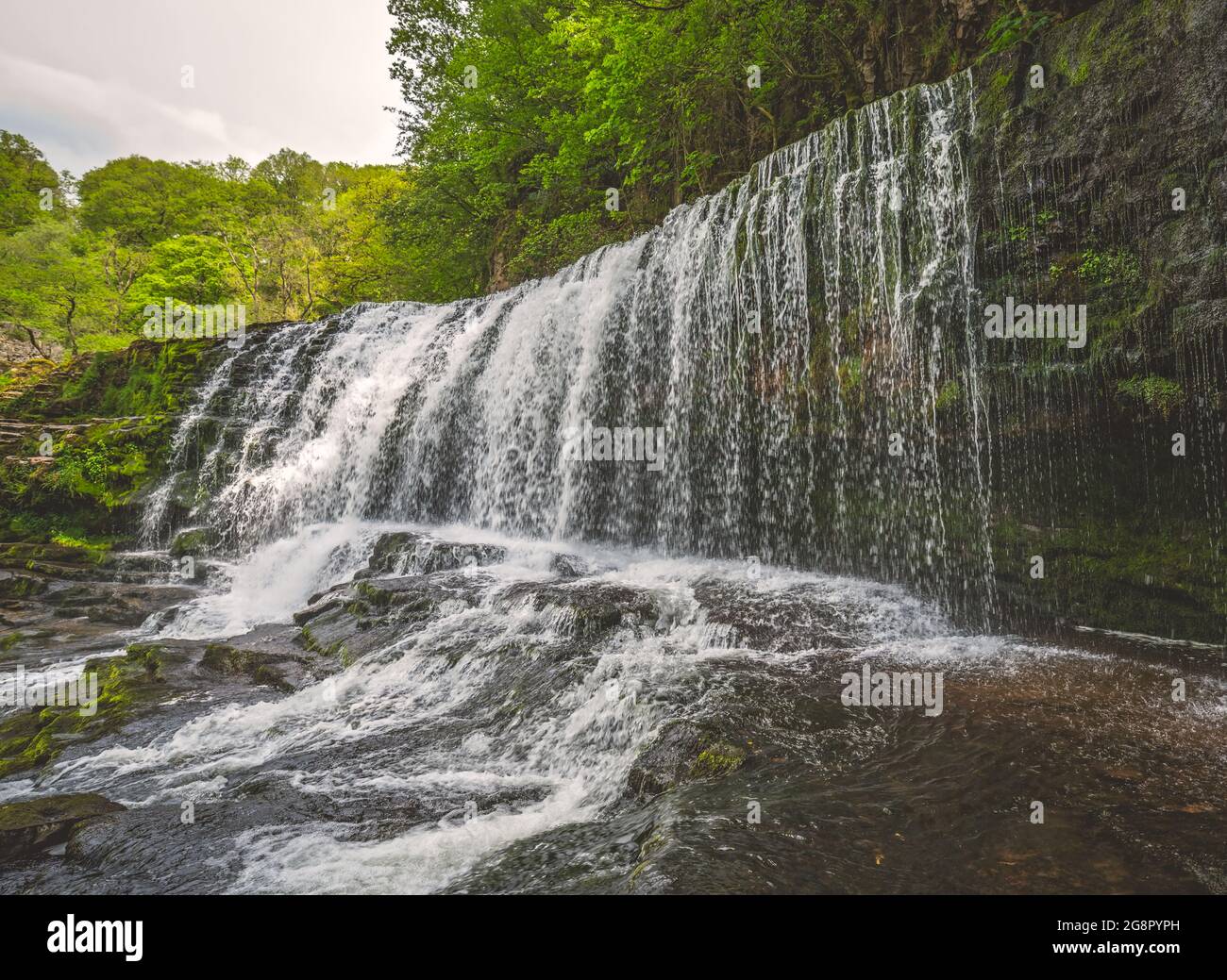 Ein Wasserfall, umgeben von Moos, Bäumen und Steinen in Ystradfellte Neath UK Stockfoto