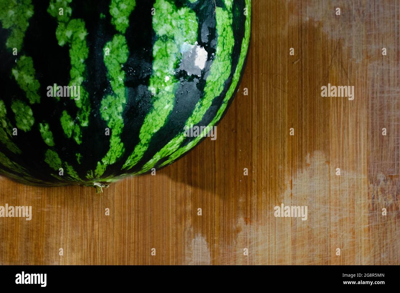 Eine frische, reife Wassermelone auf einem nassen Holzbrett. Fruchtkonzept für sommerliche Mahlzeiten Stockfoto