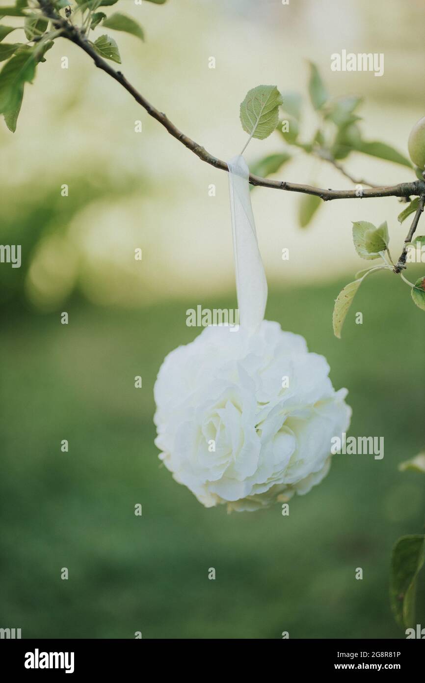 Vertikale Nahaufnahme einer weißen Blumendekoration, die vom Ast hängt. Geringer Fokus. Stockfoto