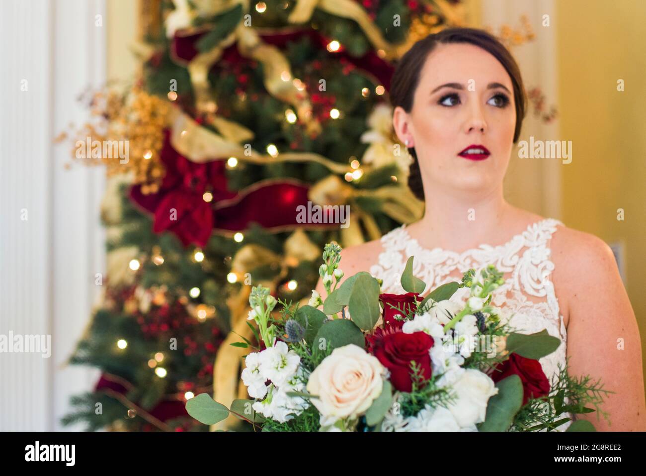 Braut mit Blumenstrauß steht am weihnachtsbaum Stockfoto