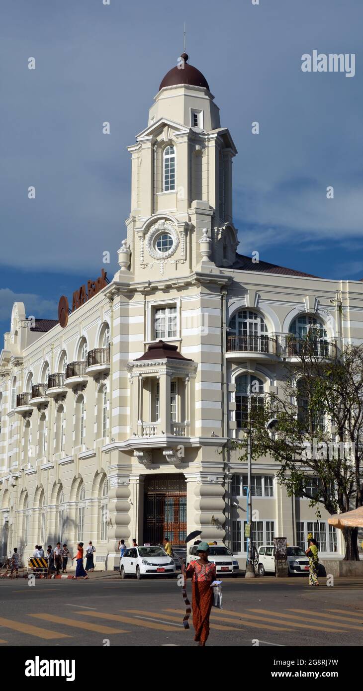 YANGON, MYANMAR (BURMA) - 25. Okt 2014: Ein Postkartenverkäufer vor dem renovierten Hauptsitz der AYA Bank, Yangon, Burma Stockfoto