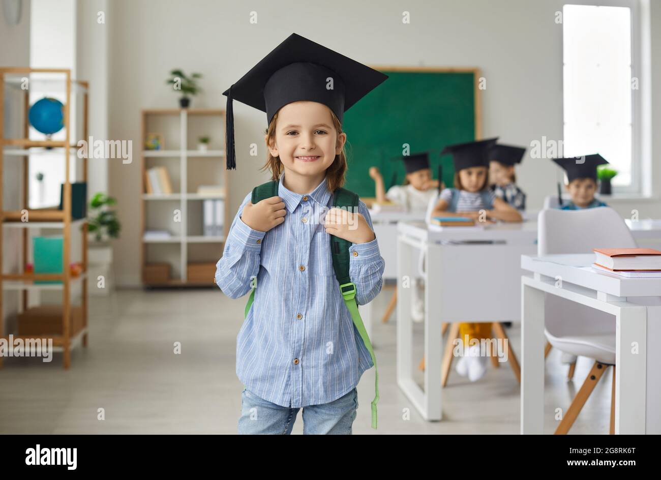 Porträt eines kleinen Grundschuljungen, der in einem Leichenbrett gekleidet ist, in einem Klassenzimmer. Stockfoto