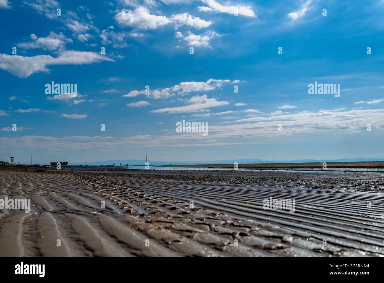 Ein fast menschenleerer Sandstrand im Morgenlicht, fotografiert aus einer sehr tiefen Perspektive. Stockfoto