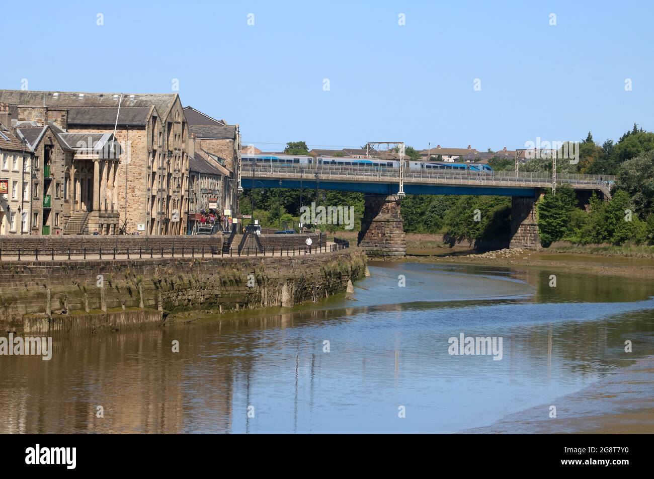 Blick auf den Fluss Lune in Lancaster, vorbei am St. George's Quay, zur Carlisle Bridge mit dem Elektrozug der West Coast Main Line, 17. Juli 2021. Stockfoto