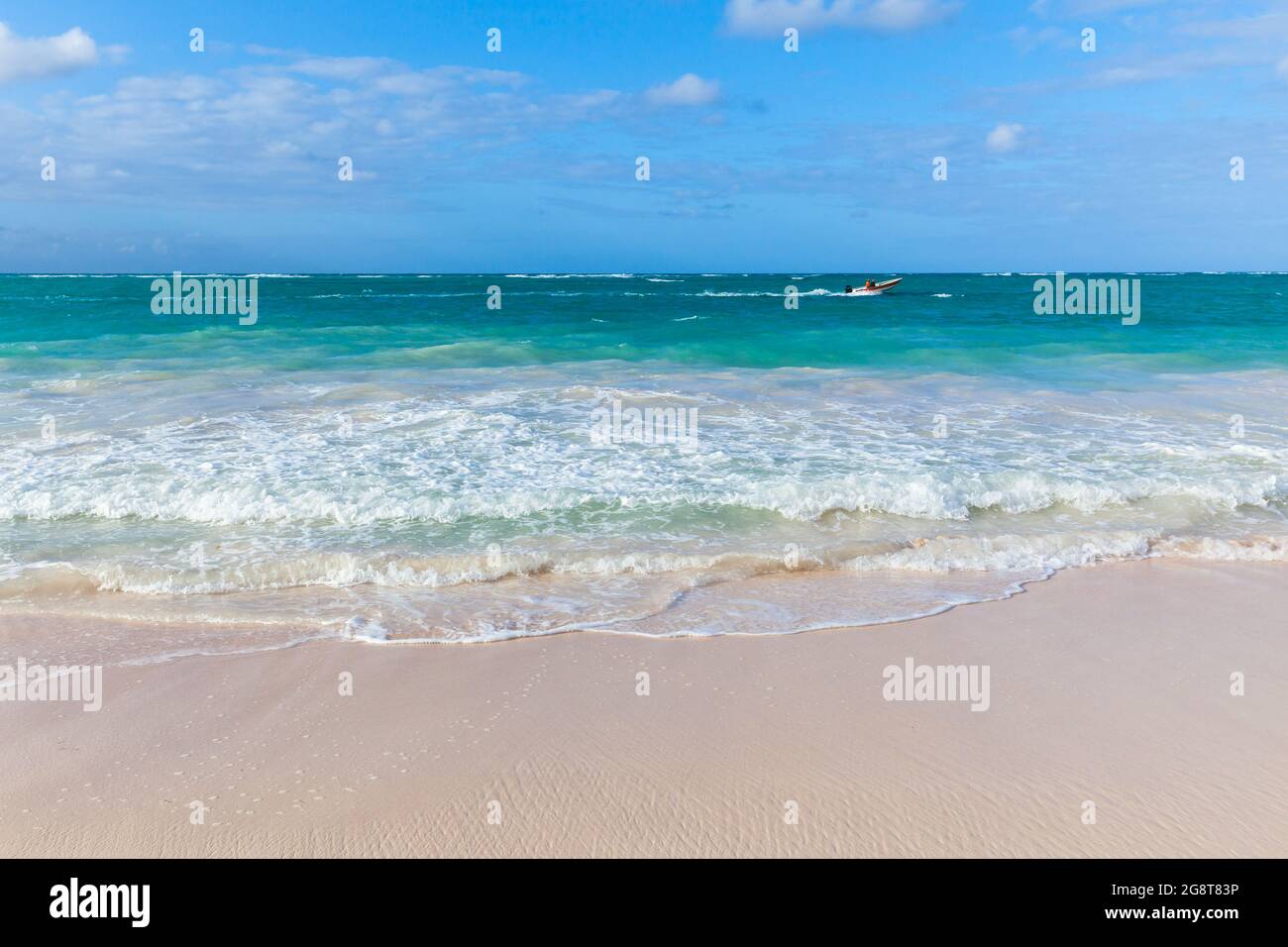 An einem sonnigen Tag fährt ein kleines Motorboot entlang des Bavaro-Strandes, der Küstenlandschaft der Dominikanischen Republik Stockfoto