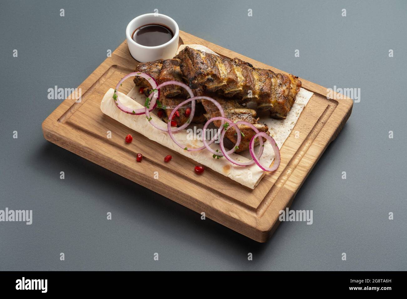 Schaschlik oder gegrillte Fleischrippchen mit Sauce und Zwiebel auf Pita auf Holzbrett Stockfoto