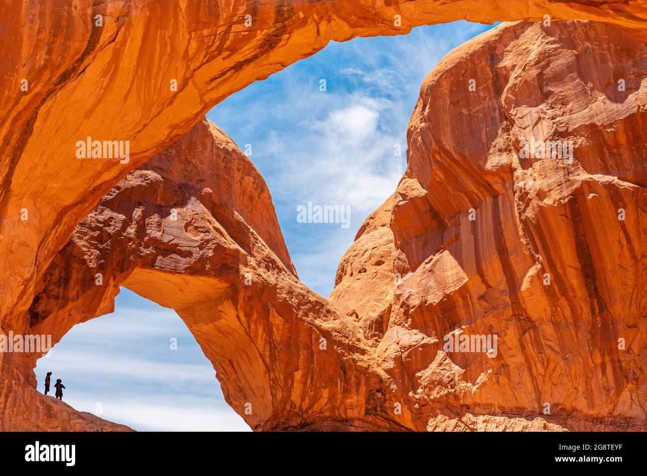 Doppelbogen mit Silhouette von zwei Personen, Arches Nationalpark, Utah, USA. Stockfoto