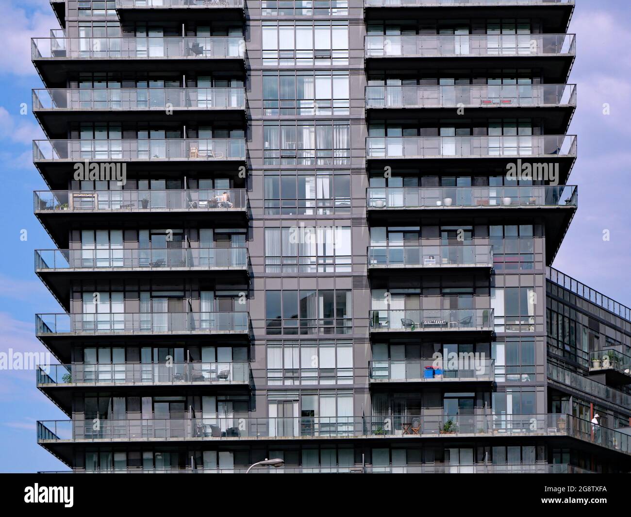 Modernes Hochhausgebäude mit deckenhohen Fenstern und Balkongeländern aus Glas für maximalen Zugang zu Sonnenlicht Stockfoto