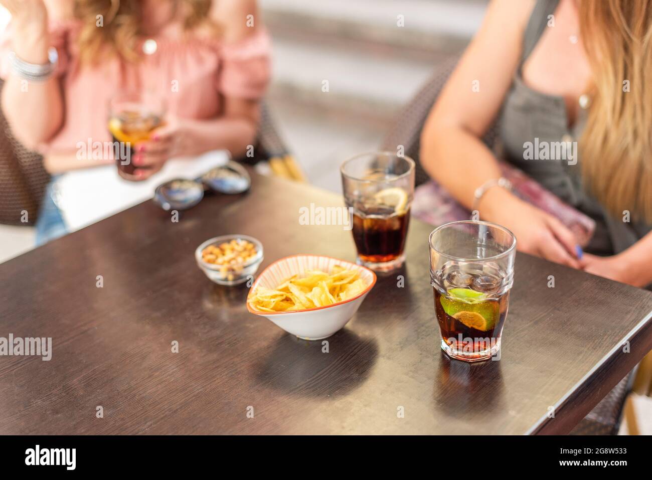 Beschnittene Ansicht einiger Getränke und Snacks, die von erwachsenen Freunden konsumiert werden Stockfoto