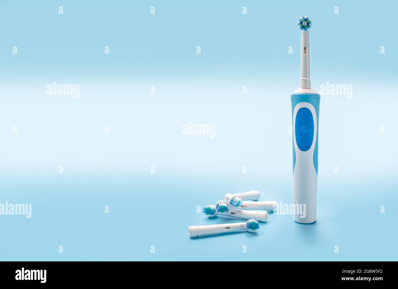 Moderne elektrische Zahnbürste und Ersatzköpfe auf blauem Hintergrund. Modernes Set mit Schallzahnbürsten oder elektrischen Zahnbürsten mit Ersatzköpfen. Platz zum Kopieren Stockfoto