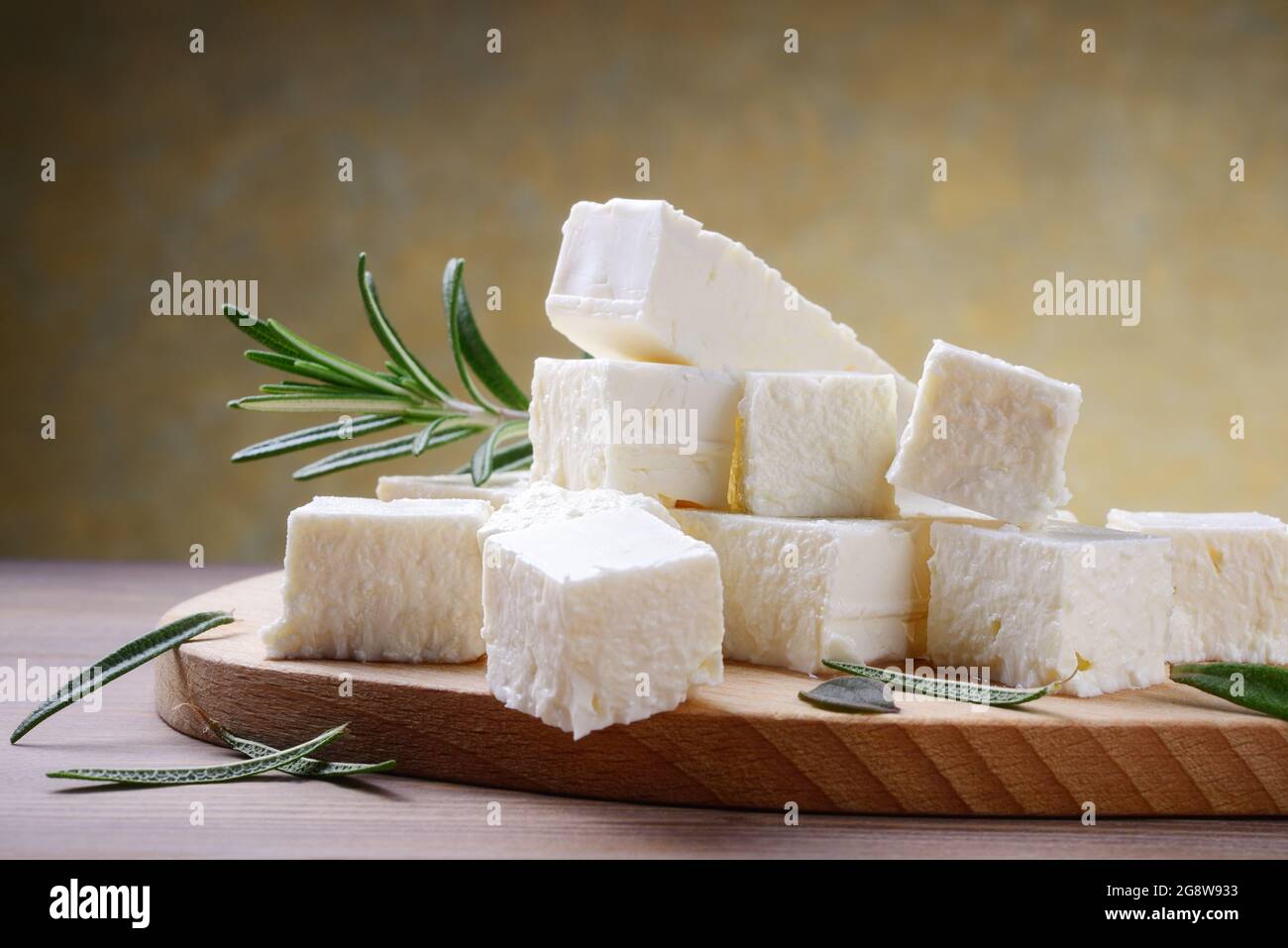 Fetakäse mit Rosmarin auf Holzschneidebrett, selektiver Fokus, Platz für Text, Nahaufnahme. Stockfoto