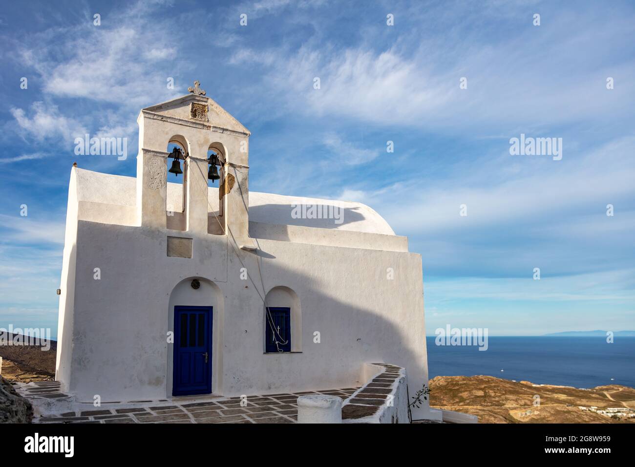 Kirche orthodoxe, kleine weiß getünchte alte Kapelle, kletterte auf felsigen Berg bei Serifos Insel über Chora, Kykladen Griechenland. Ruhiges Ägäisches Meer und blau bewölkt Stockfoto
