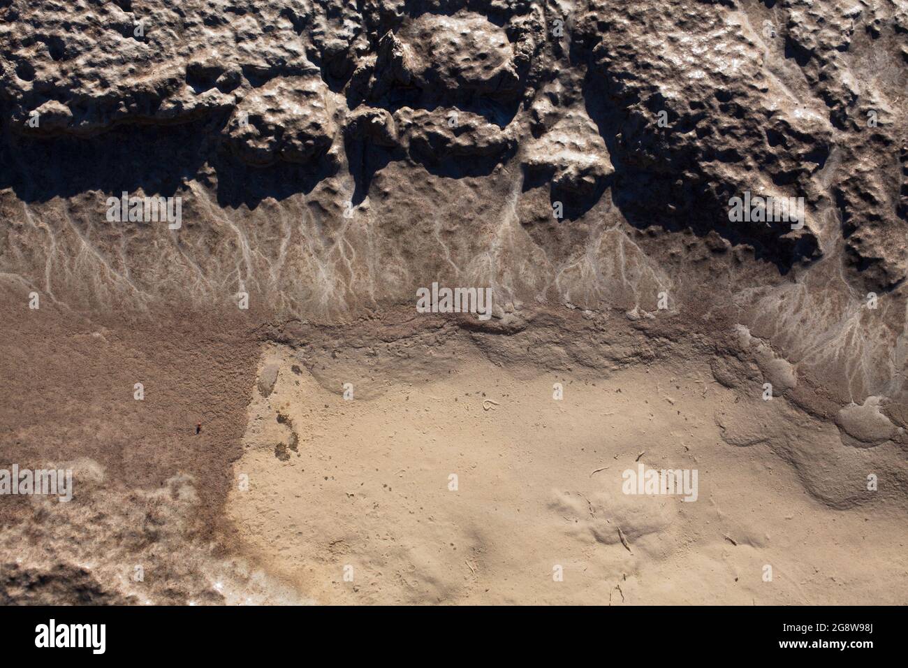 Mikroskalige geografische Merkmale im Schlamm nach einer Flußflut. Die Landschaft sieht aus wie Satellitenbilder, mit Schluchten, Flusstälern und Deltas. Stockfoto