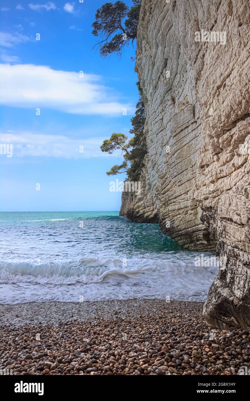 Italien entdecken: Typischer Kiesstrand mit Klippe von Apulien in Süditalien. Natur entspannen: Zagare Bucht im Gargano Nationalpark. Stockfoto