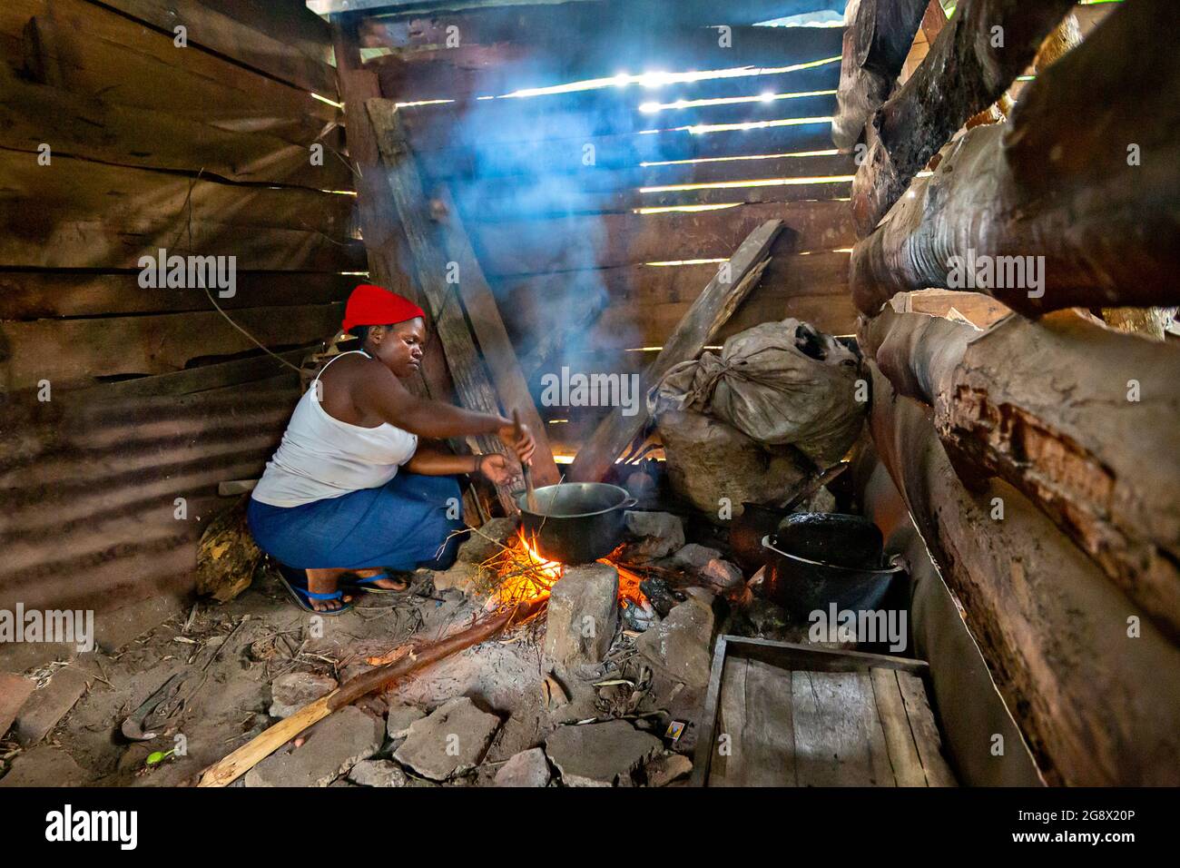 Eine Frau, die in der Dorfhütte in Kibale, Uganda, das Feuer anzündet Stockfoto