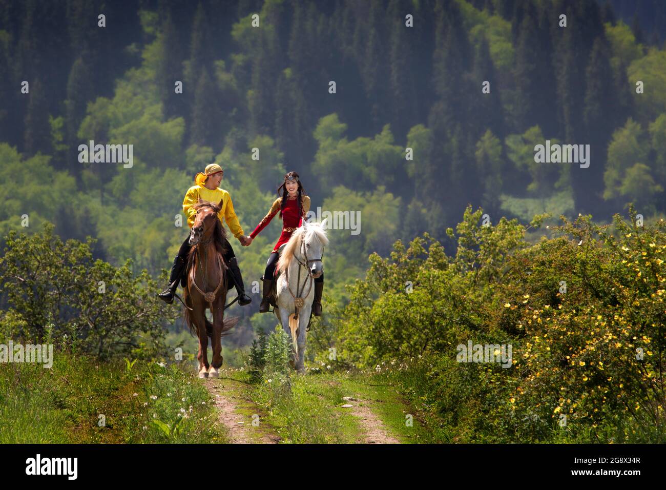Kasachische Paare in Nationaltrachten Hand in Hand auf ihrem Pferd in Almaty, Kasachstan. Stockfoto
