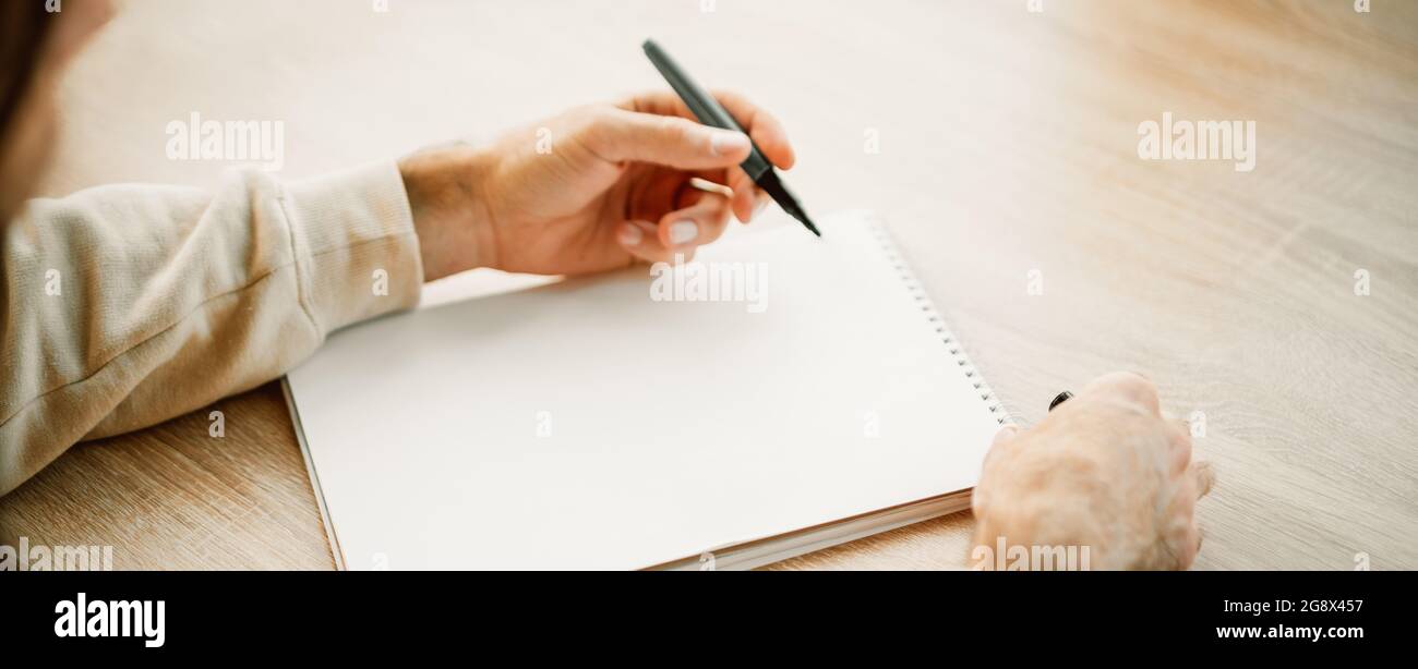 Banner eines Kakausers Hände Schreiben in einem leeren Papier Notizbuch mit einem Stift, Projektplanung, Erstellen einer Einkaufsliste. Notizblock mit Platz für Text Stockfoto