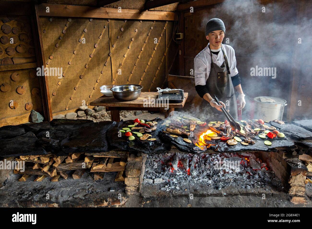 Der kirgisische Koch grillt Fleisch auf traditionelle Weise auf der Steinplatte in Bischkek, Kirgisistan Stockfoto