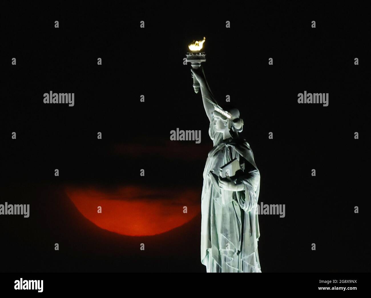 New York, Usa. Juli 2021. Am Freitag, den 23. Juli 2021, geht hinter der Freiheitsstatue in New York City ein voller Buck-Mond unter, der teilweise von Wolken verdeckt wird. Foto von John Angelillo/UPI Credit: UPI/Alamy Live News Stockfoto