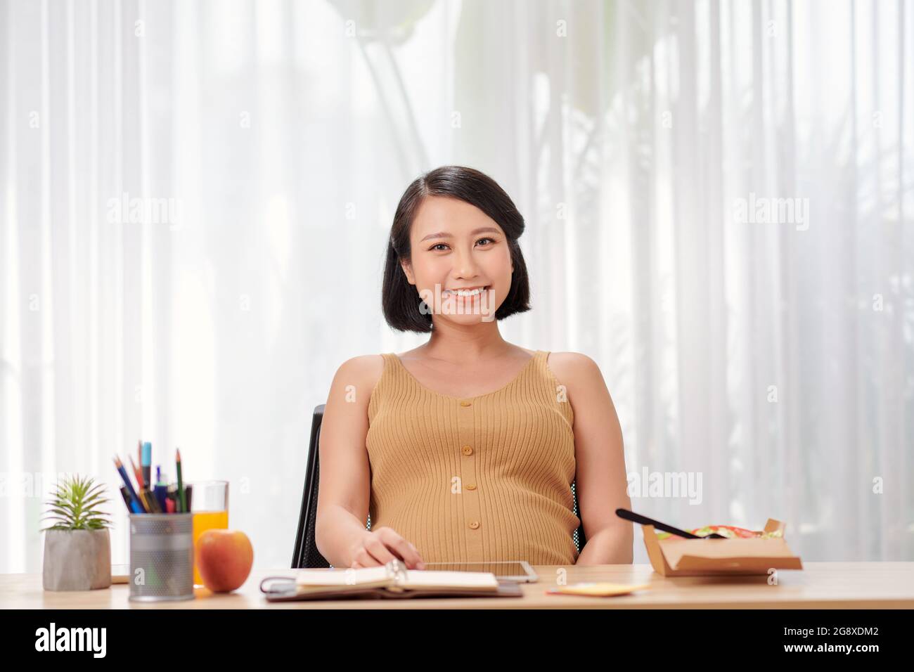 Schwanger asiatische Frau arbeitet von zu Hause in modernen weißen Büro Stockfoto