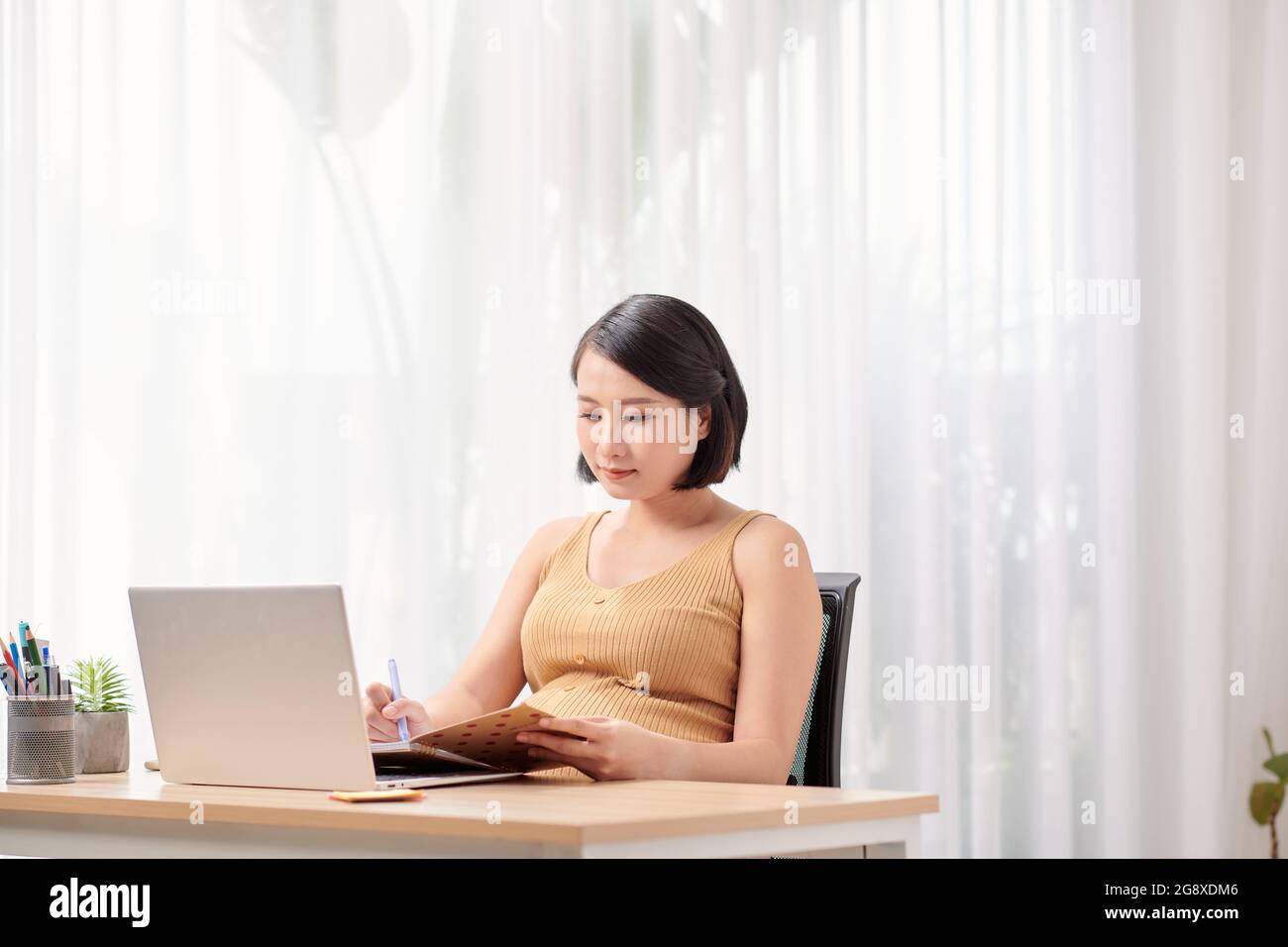Schwanger Dame In Headset Studie Mit Laptop Zu Hause Stockfoto