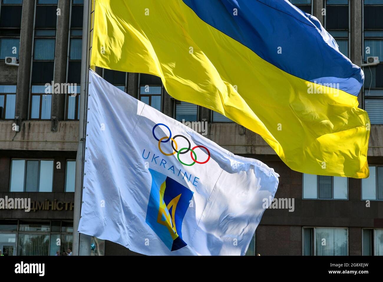 ZAPORIZHZHIA, UKRAINE - 23. JULI 2021 - die Flaggen der Ukraine und des Nationalen Olympischen Komitees werden vor der regionalen Sta Zaporizhzhia erhoben Stockfoto