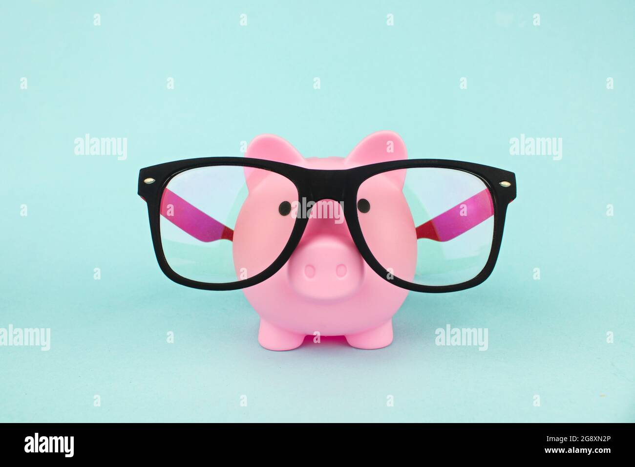 Rosa Sparschwein trägt eine Brille. Sparkonzept Stockfoto