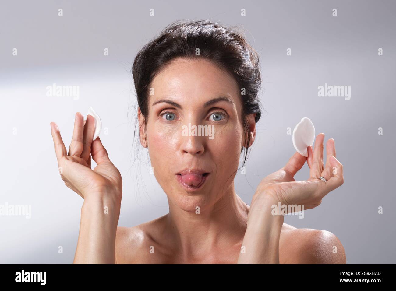 Eine Frau, die Spaß mit einem Paar Wattepads hat. Ihre Zunge herausstreckt. Stockfoto