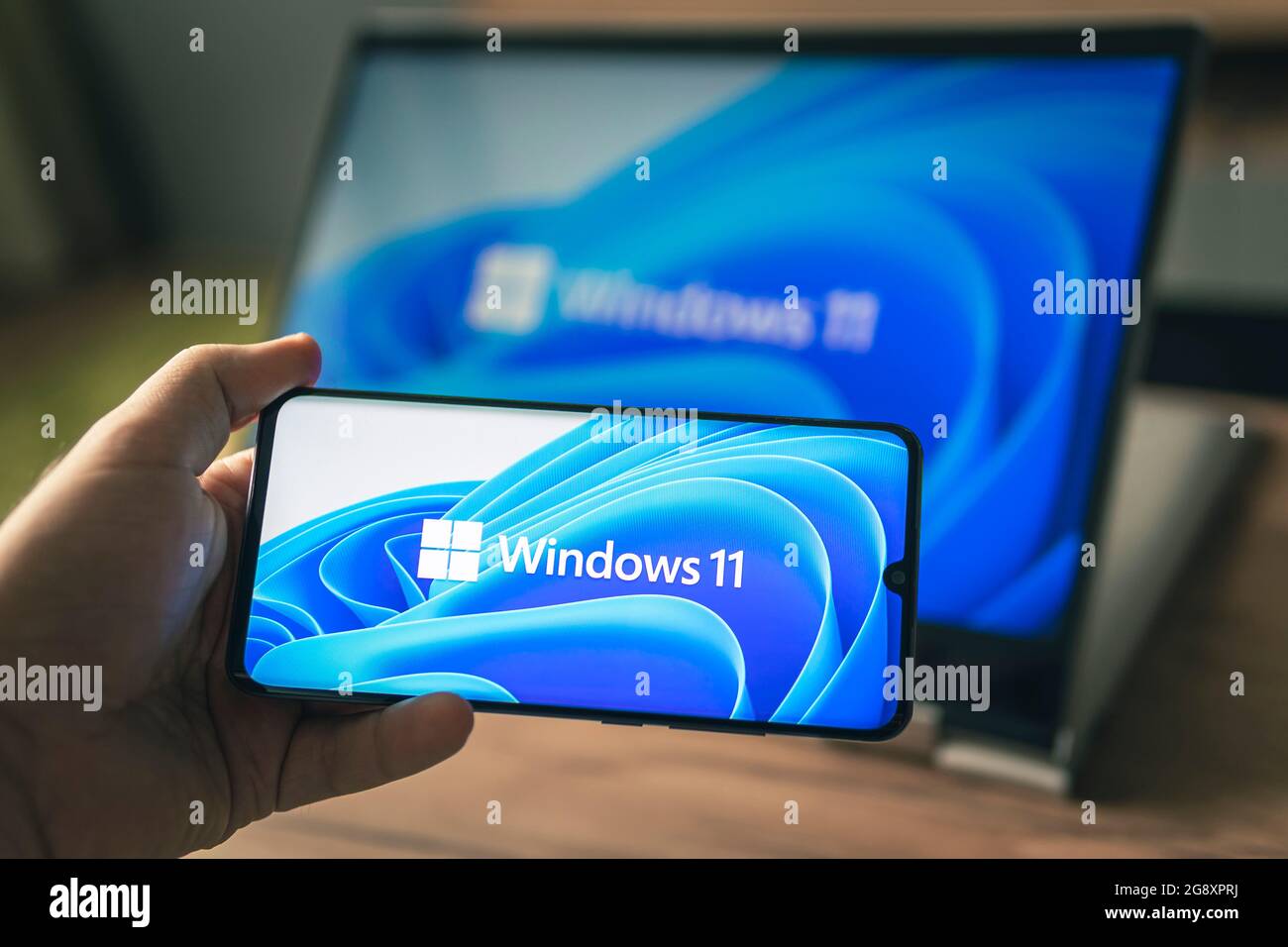 23. Juni 2021. Barnaul, Russland. Mann mit einem Laptop und einem Smartphone, Windows 11 neues Microsoft-Betriebssystem auf den Bildschirmen Stockfoto