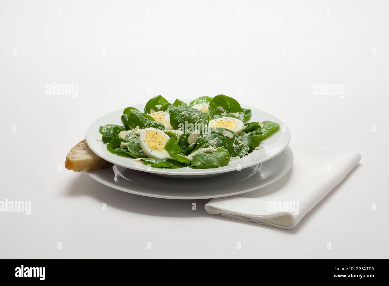 Ein gesunder, frischer Spinatsalat mit Mandeln, hartgekochtem Ei, Feta und einem harten Parmesan im romano-Stil Stockfoto