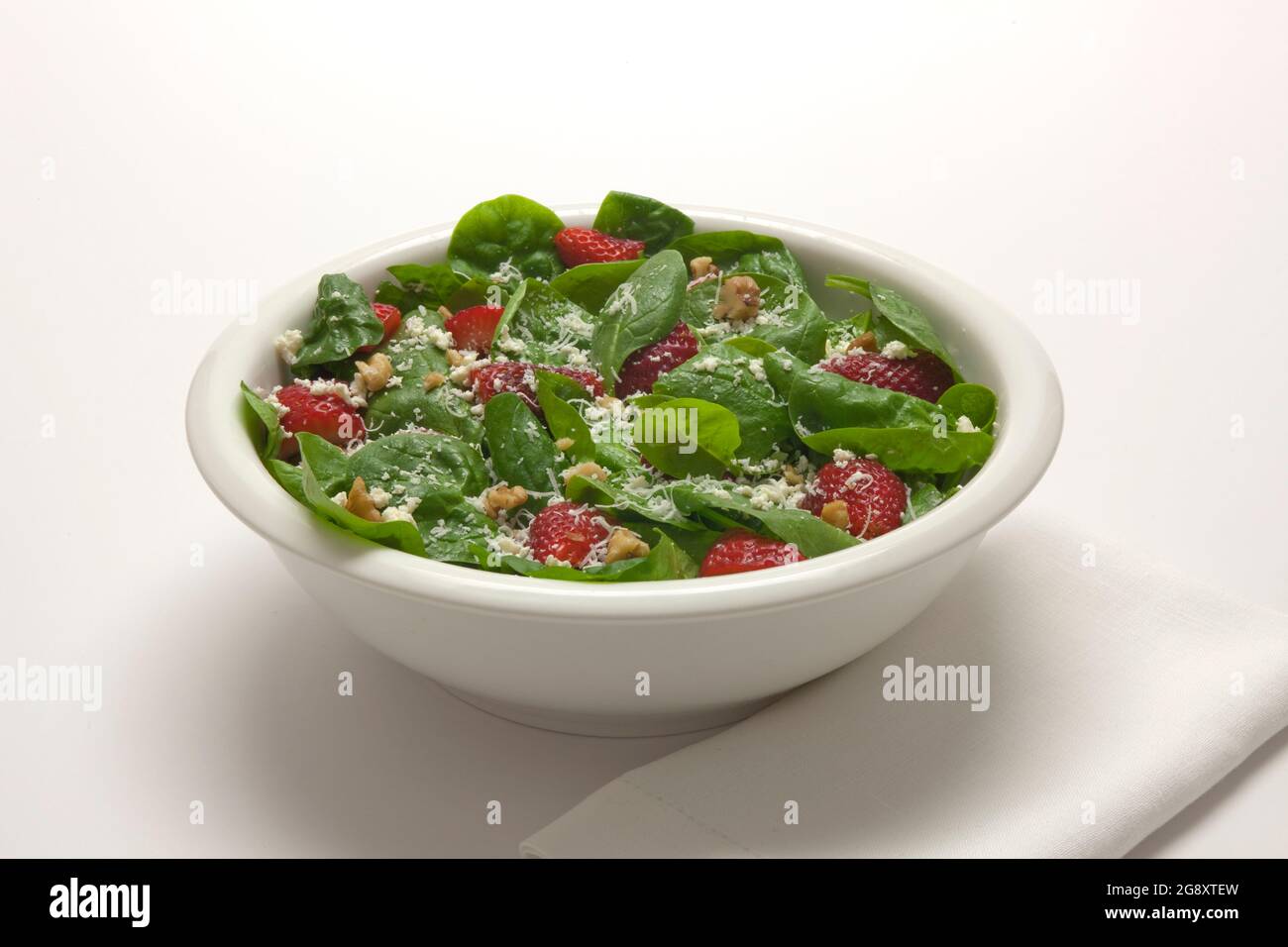 Ein gesunder, frischer Spinatsalat mit Streubeeren, Feta-Käse, Walnüssen und einem harten Parmesan im romano-Stil Stockfoto