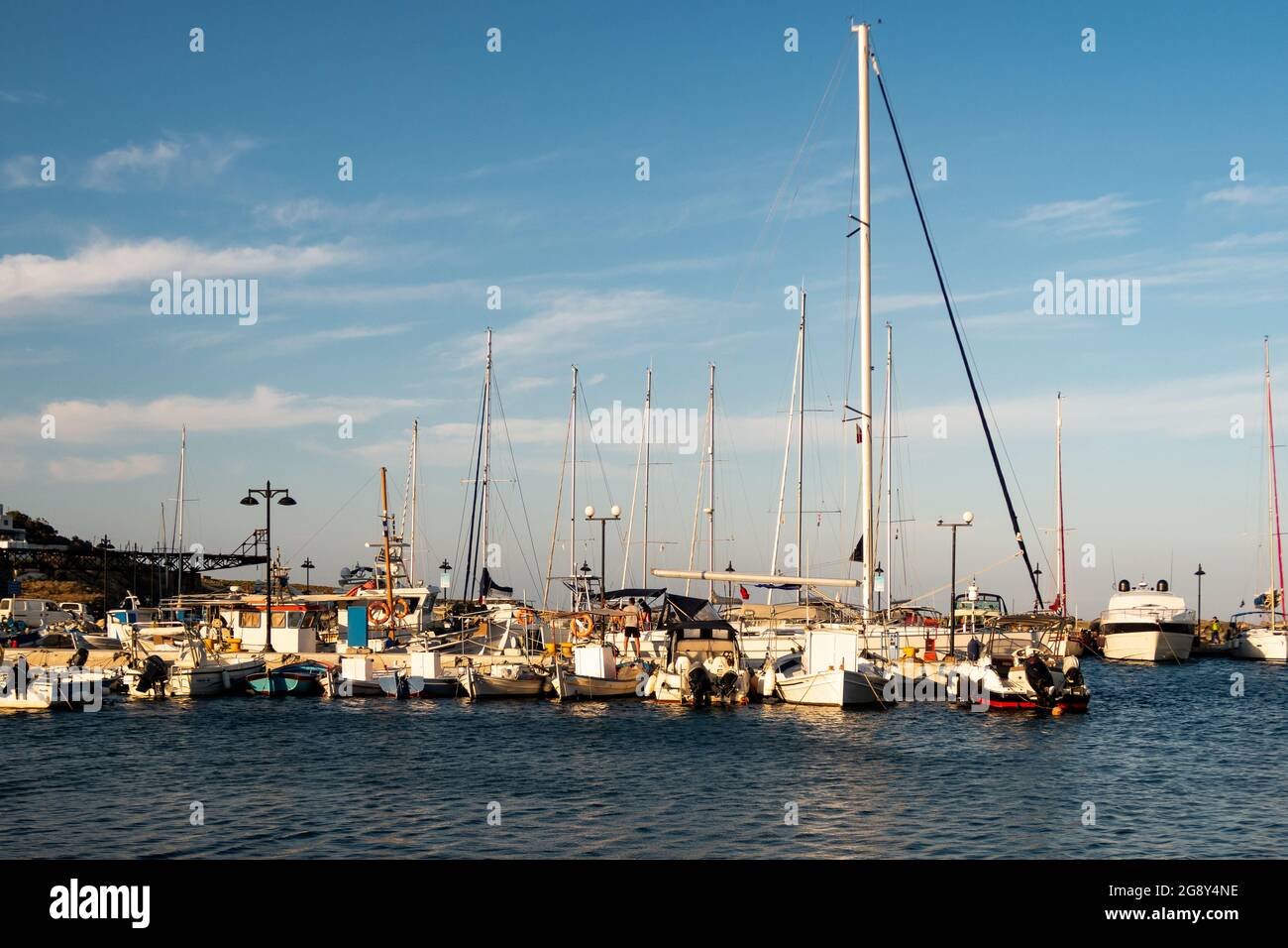 LOUTRA, Kythnos, Griechenland, 03/06/2019. Reihe von Segel- und Fischerbooten, die bei Sonnenuntergang am Pier in Loutra Marina Kythnos, Kykladen-Inseln, festgemacht sind. Stockfoto
