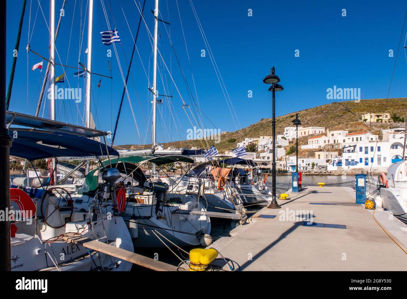 LOUTRA, Griechenland, 03.06.2019. Pier in Loutra Marina Kythnos mit Segelbooten, Laternen und traditionellen griechischen weiß getünchten Häusern. Stockfoto