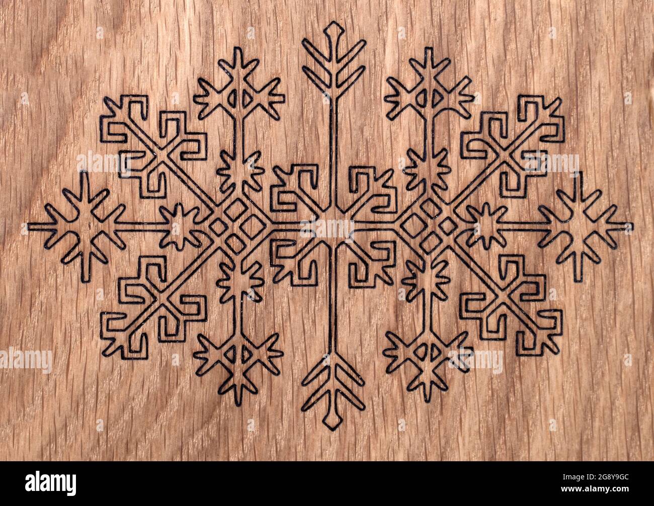 Lettische antike Ornamente in Holz verbrannt; auf Holzplatte abgebildet Stockfoto